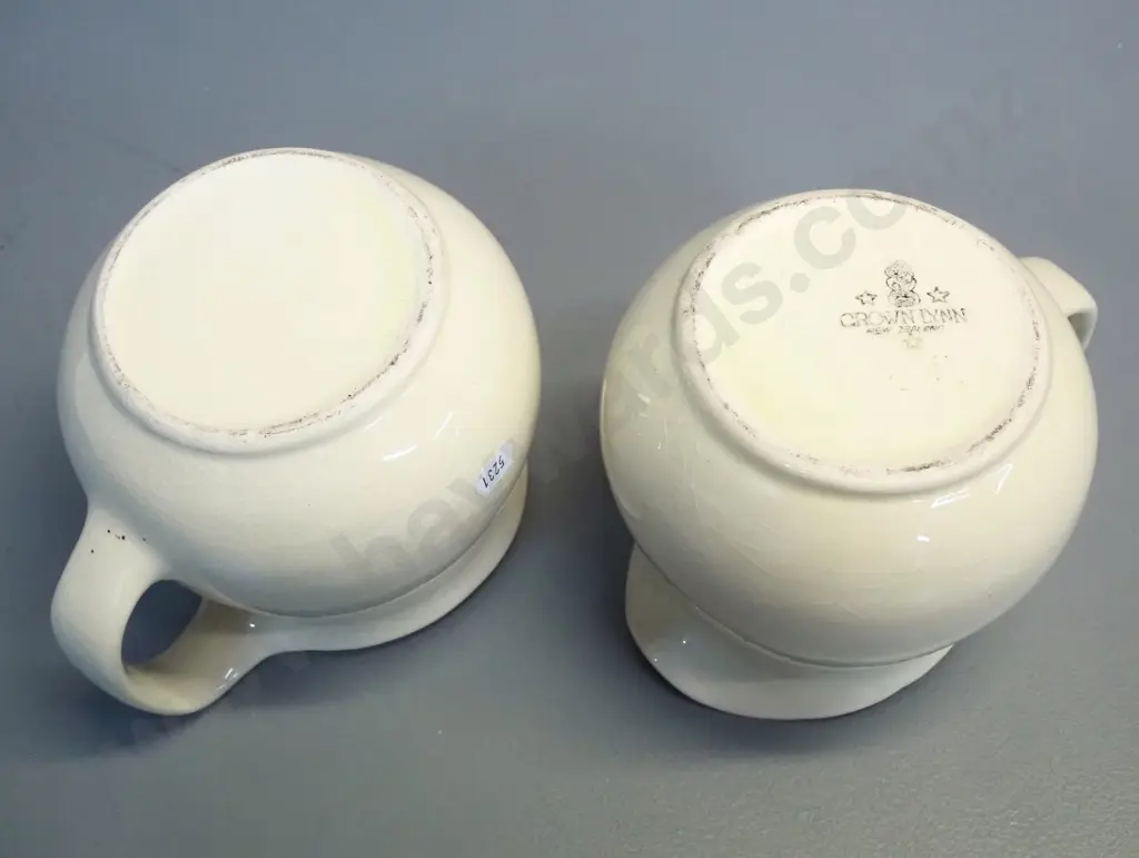 2 early Crown Lynn cream glaze milk jugs - one with tiki mark, both stamped 709-3. Some crazing. H-140 W-170 at handle Image 1++
