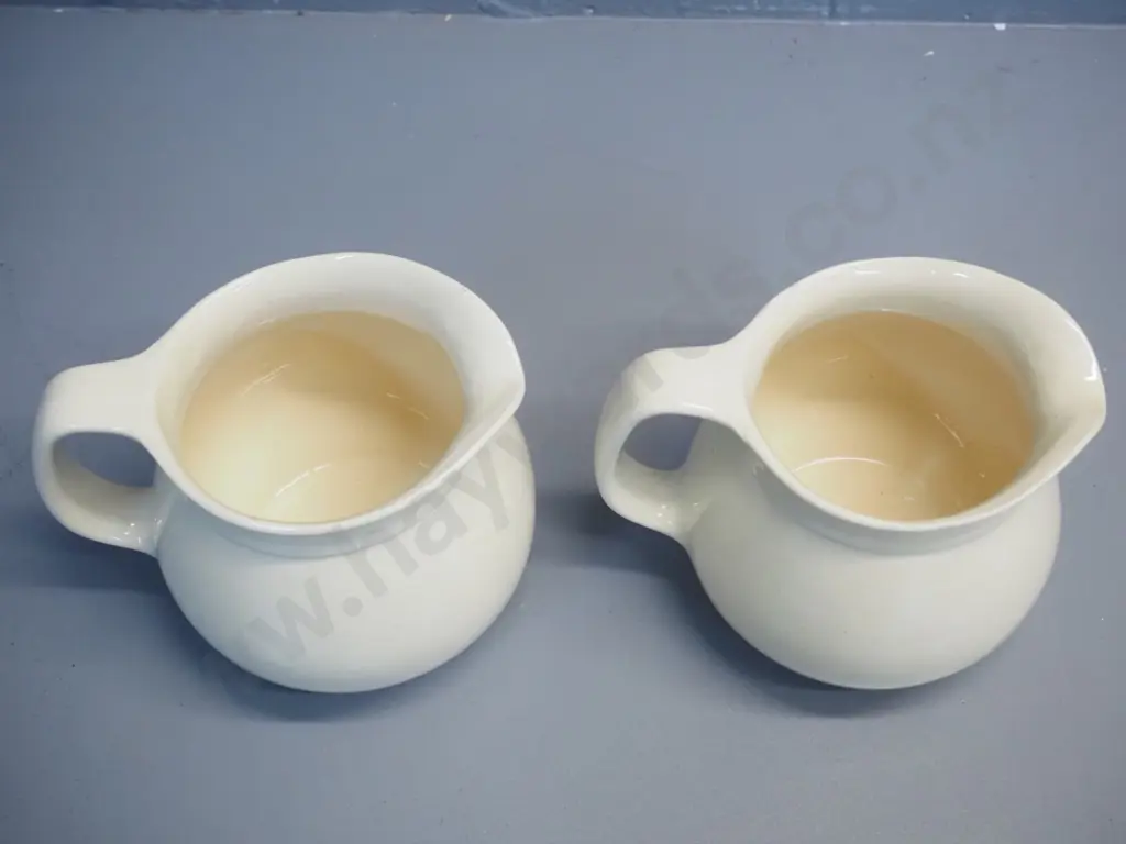 2 early Crown Lynn cream glaze milk jugs - one with tiki mark, both stamped 709-3. Some crazing. H-140 W-170 at handle Image 1++