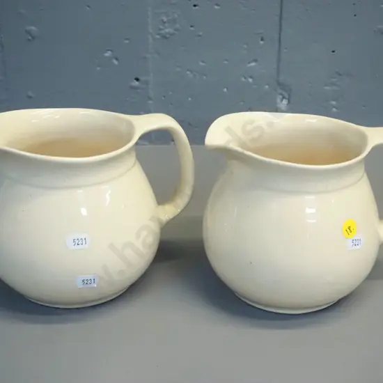 2 early Crown Lynn cream glaze milk jugs - one with tiki mark, both stamped 709-3. Some crazing. H-140 W-170 at handle