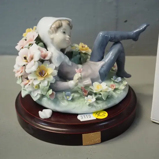 Lladro figure of pixie reclining in flowers, 1 leaf chipped off. H100 L130, comes with composite base & original box