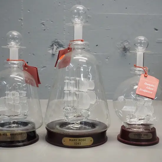 3 Dunelm glass ship sculptures in stoppered bottles with wooden stands