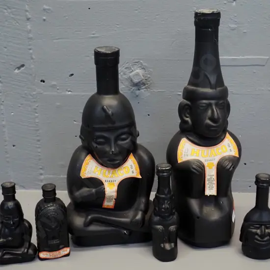 Huaco Italian brandy in figural black glass bottles - two 750ml bottles and 4 miniatures, sealed with contents