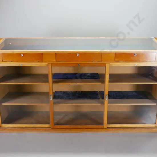 large kauri shop display cabinet with sloping glass top w/3 access flaps & 3 sliding doors in base, all lockable, with