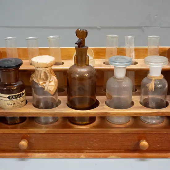 vintage wooden chemist's stand with assorted bottles, test tubes, and mineral samples in drawer