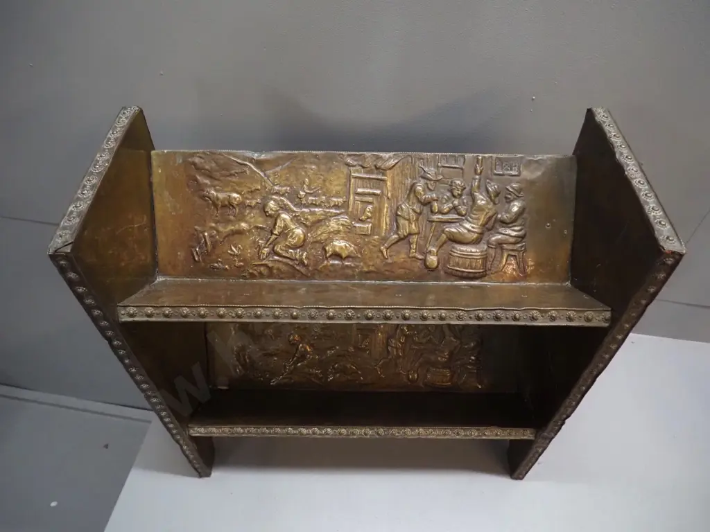 2-tier timber open-back bookcase with angled shelves, all covered in beaten brass with various figural scenes H420 W490 Image 1++