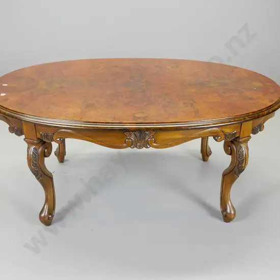 reproduction walnut and mahogany oval coffee table having scrolling shaped apron,