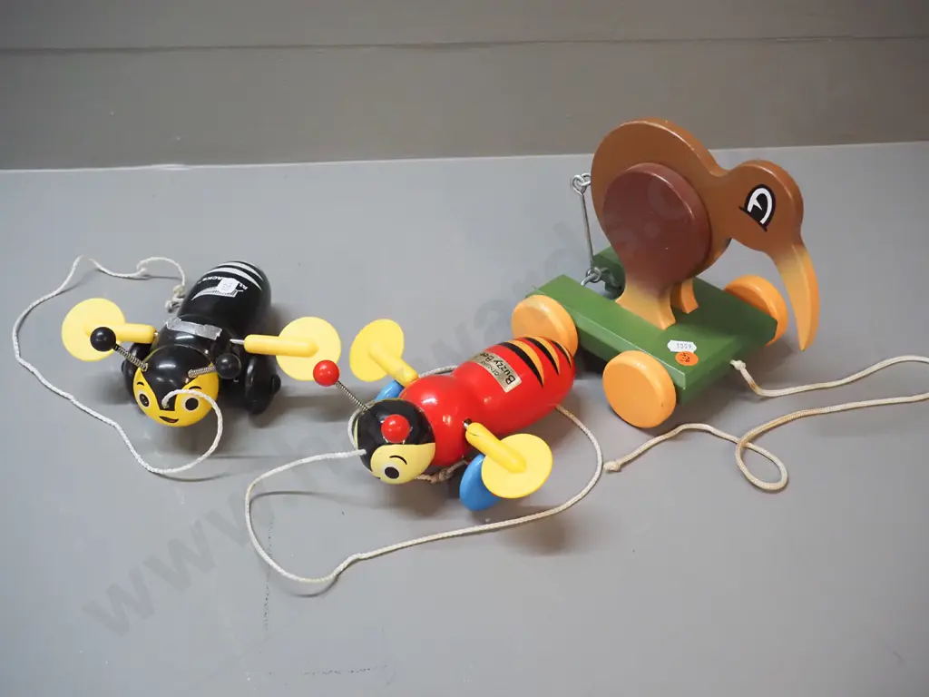 3 New Zealand wooden toys: pull along kiwi bird on wheels designed by Dick Frizzell and 2 buzzy bees, one is All Blacks Image 1++