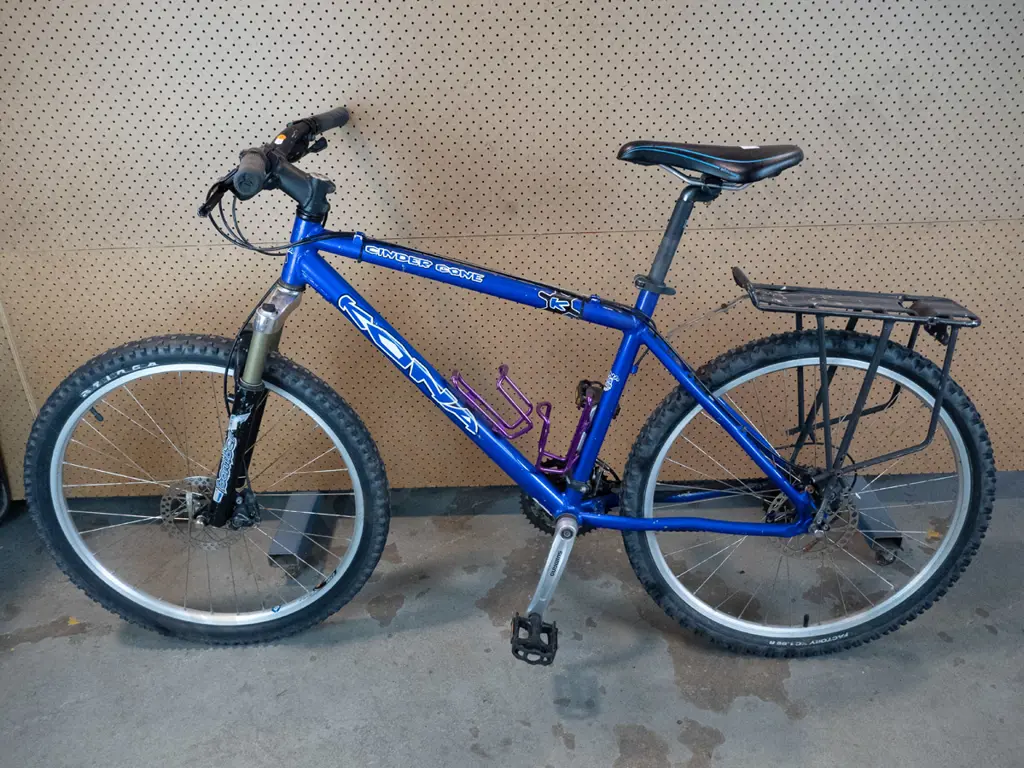 Blue Kona Bike with two purple cupholders and bag rack on back Image 1++