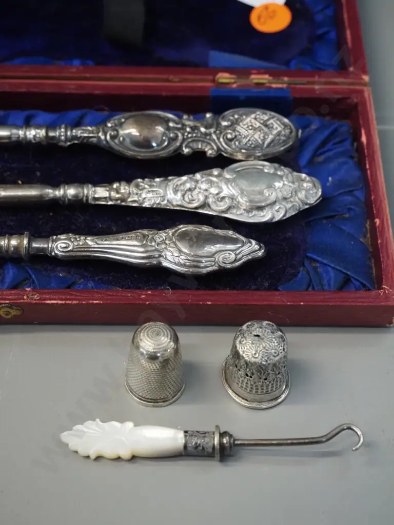 3 sterling silver handled button hooks in fitted case, 2 thimbles, one marked sterling, and a small mother of pearl Image 1++