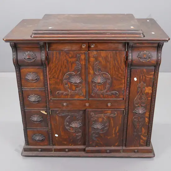 oak cupboard with lift up lid above two sets of central cupboard doors, flanked by five small drawers on one side