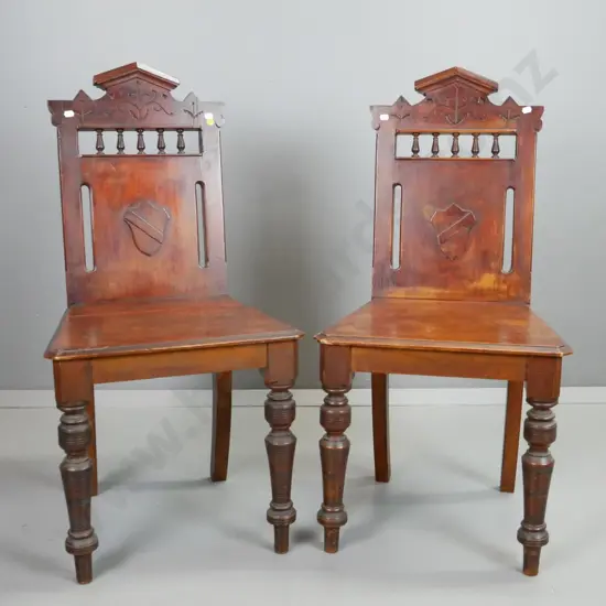 pair of Colonial rimu hall chairs, with turned front legs, spindle gallery, shield armorial, etc. Join split in seat