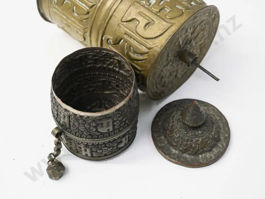 2 pressed metal prayer wheels - one brass with wood & metal spindle, L-230, smaller has weight on chain, top comes off Image 1++