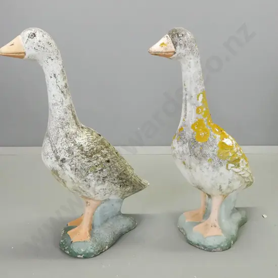 pair of concrete garden geese with painted details, overall lichen and patination, a few chips and a crack that may be a