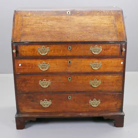 late Georgian country oak drop-front desk with fitted interior pigeonoles, 5 drawers with brass knobs, cross-banded top,