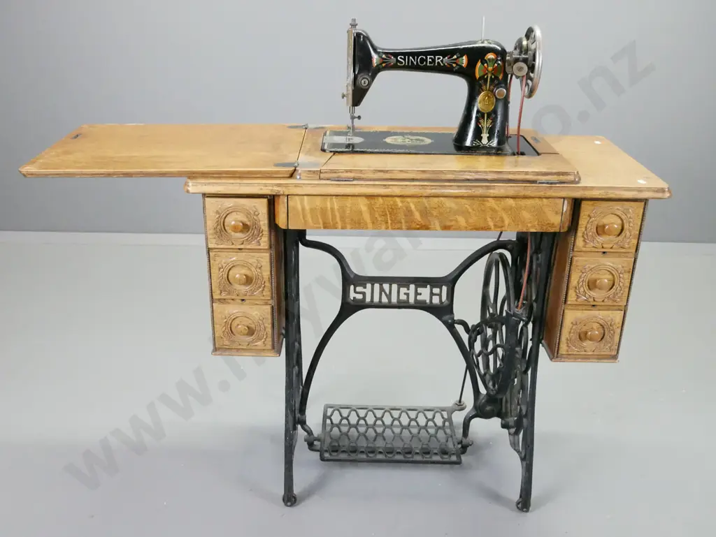 Singer treadle sewing machine with cast iron base, oak cabinet, press carved decoration, vintage fan marked Singer in Image 1++