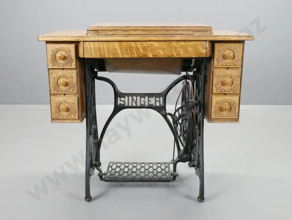 Singer treadle sewing machine with cast iron base, oak cabinet, press carved decoration, vintage fan marked Singer in Image 1++
