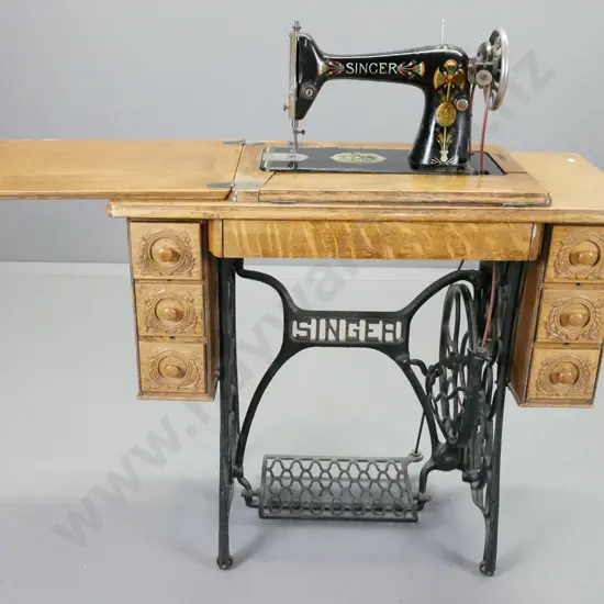 Singer treadle sewing machine with cast iron base, oak cabinet, press carved decoration, vintage fan marked Singer in