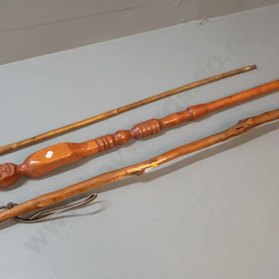 3 walking sticks - one with figural carving and inch markings, one with leather bound handle end, and one rustic walking