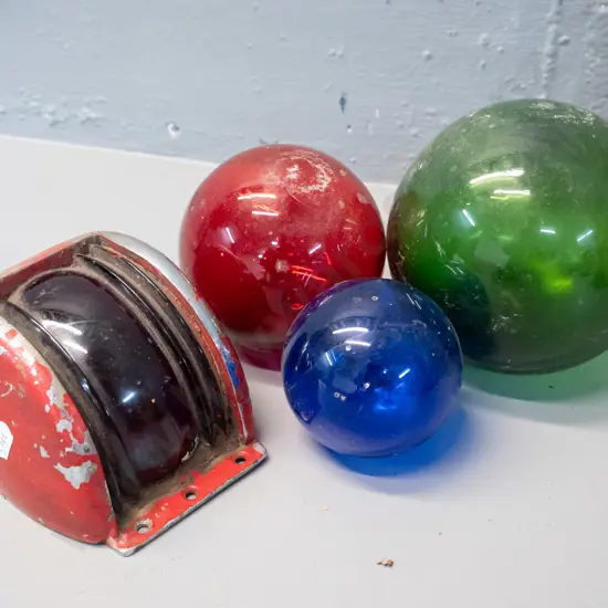 vintage cast metal port side ship light cover with red fresnel lens and 3 small coloured glass fishing floats. Some