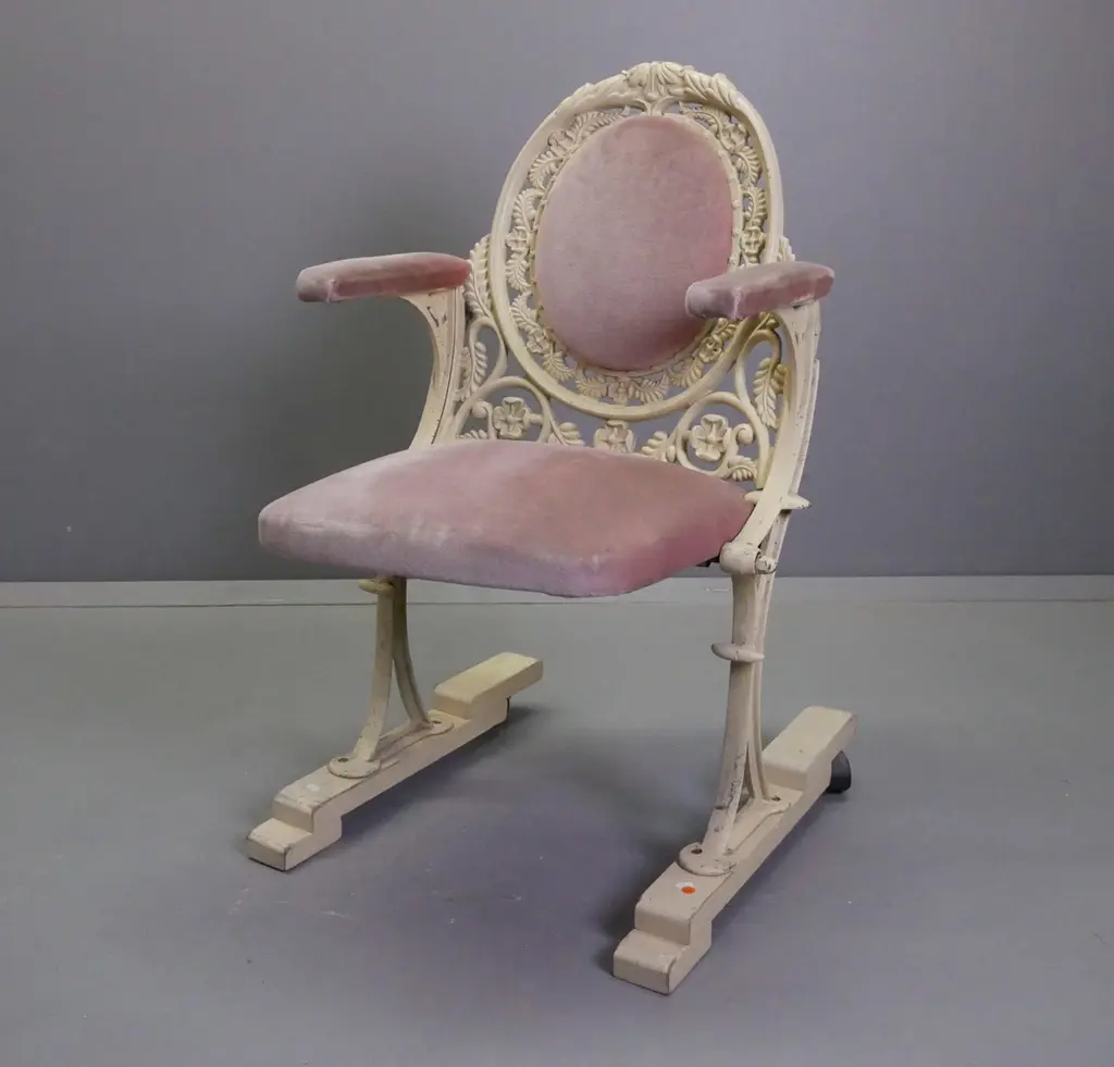 cast metal flip-up theatre seat on wooden base with casters on the back, salmon pink upholstery, ex St James Image 1++
