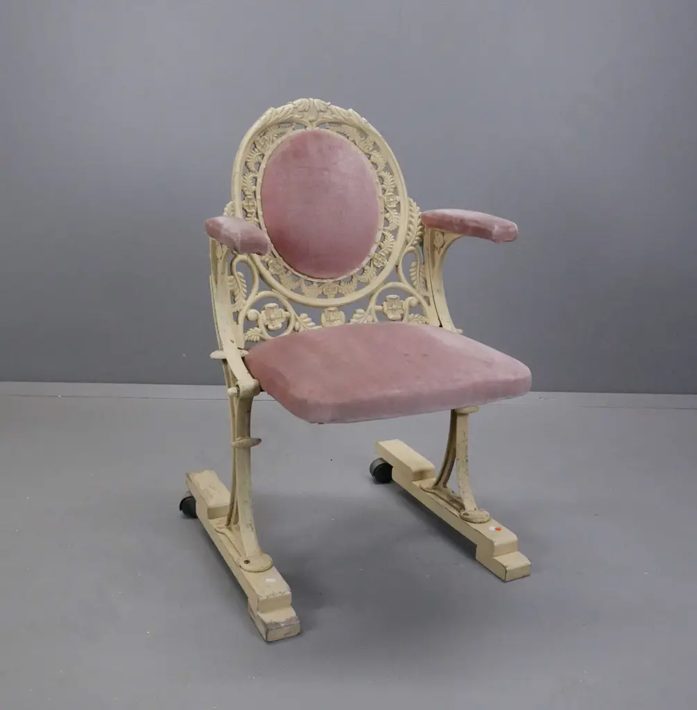 cast metal flip-up theatre seat on wooden base with casters on the back, salmon pink upholstery, ex St James Image 1++