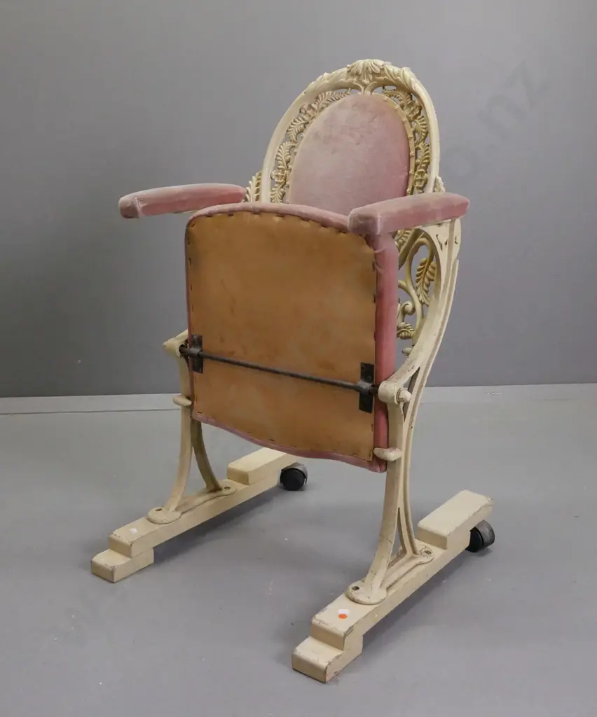 cast metal flip-up theatre seat on wooden base with casters on the back, salmon pink upholstery, ex St James Image 1++