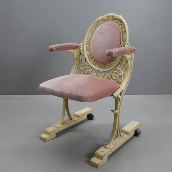 cast metal flip-up theatre seat on wooden base with casters on the back, salmon pink upholstery, ex St James