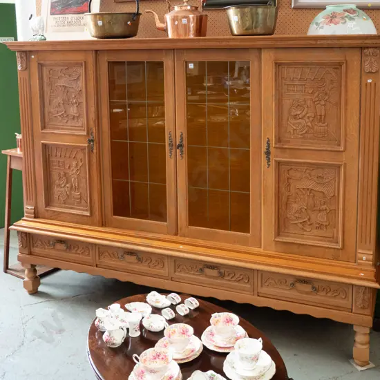 large northern European oak 4-drawer display cupboard 2 leadlight centre doors, 4 carved door panels w/village scenes,