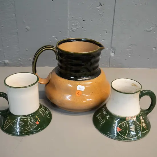 2 NZ studio pottery wide-based mugs marked PS and Carey's Bay H-100 and a Royal Doulton stoneware jug H-150. Mugs have