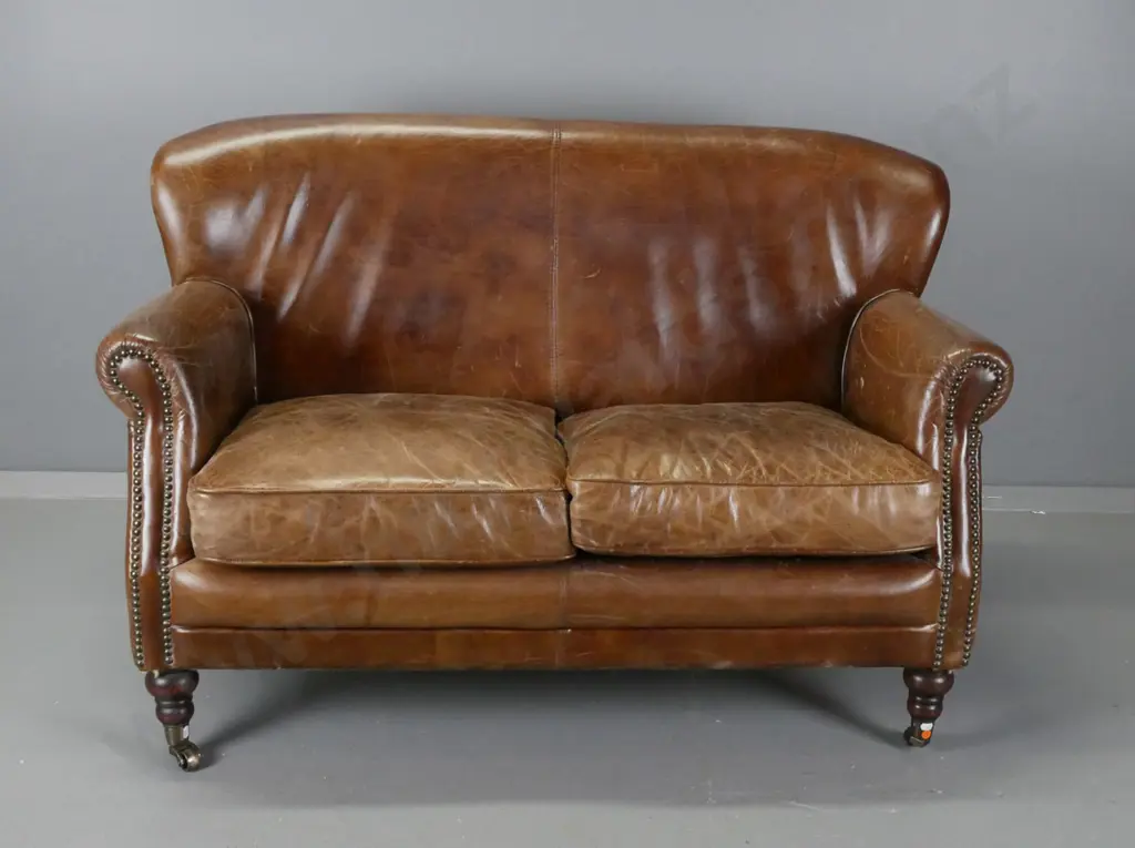 vintage rolled arm brown leather brass studded 2-seater settee on turned legs with brass cup casters - overall age wear Image 1++