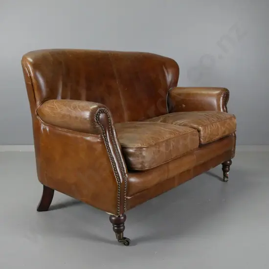 vintage rolled arm brown leather brass studded 2-seater settee on turned legs with brass cup casters - overall age wear