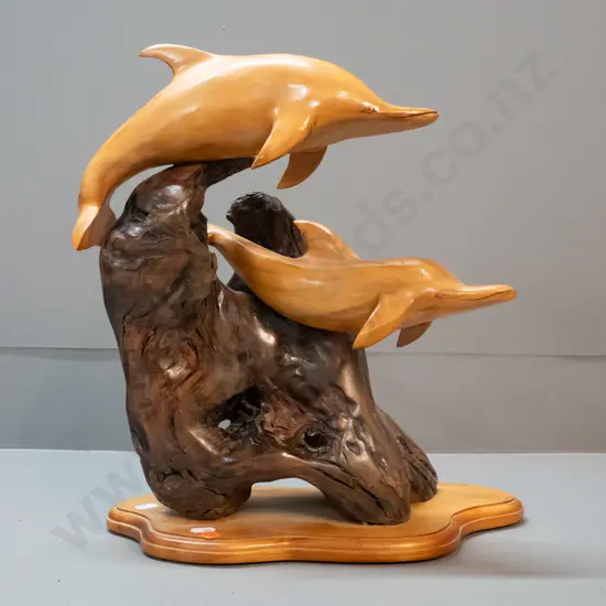 carved rimu figure of two leaping dolphins on piece of driftwood, label on base for Karaka Wood Gallery, Picton H-370