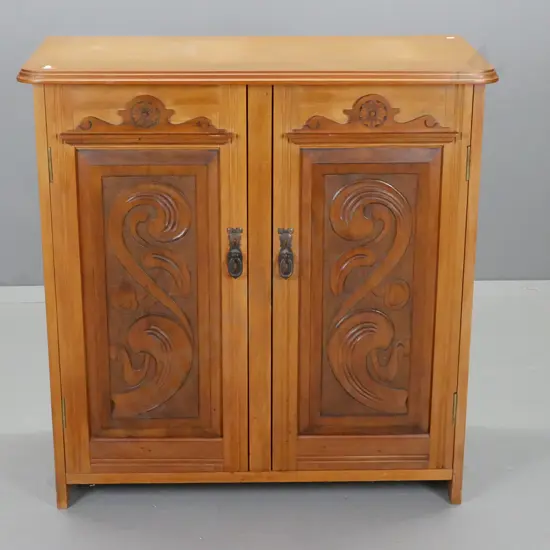 kauri and rimu 2-door cupboard with carved panelled doors and crests, drop handles, 2 interior shelves, assembled from