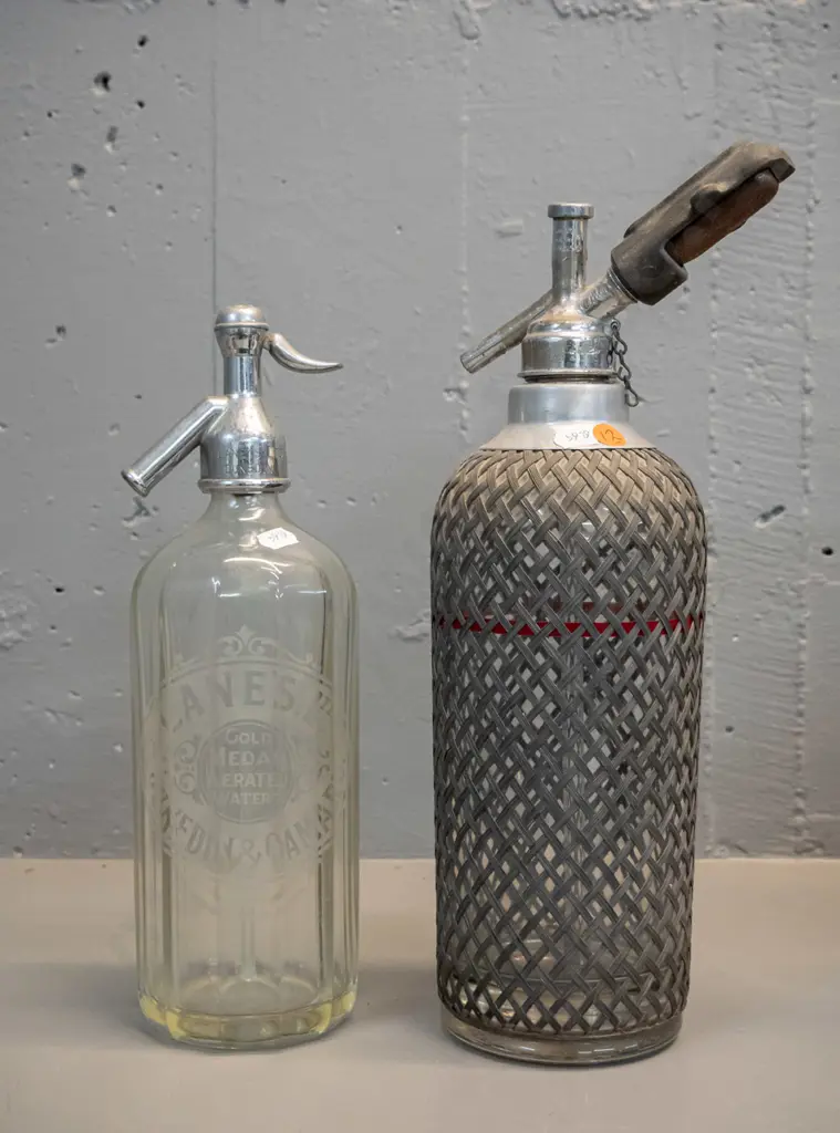 2 vintage soda syphons - one with Lane's Dunedin Oamaru mark to bottle and chrome top, other with wire mesh - some Image 1++