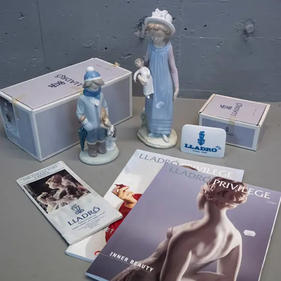 2 Lladro figurines, one with original box, a boxed Lladro plaque and 3 catalogues. Girl with doll is H-290 W-110