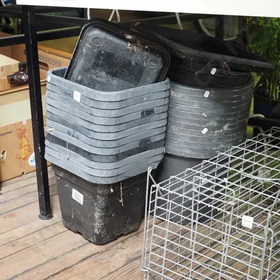 various black plastic planters in trays