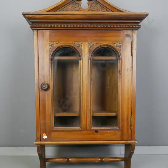 vintage pine wall-hanging cupboard with carved swan-neck pediment, door with 2 arched glazed panels, wooden knob, turned