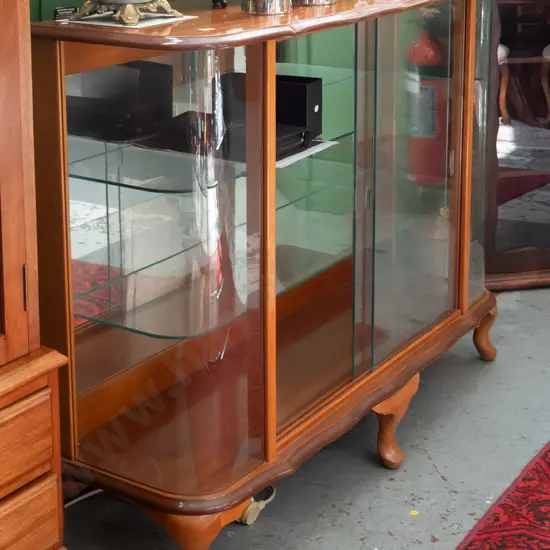 mahogany display cabinet with 2 sliding glass doors, bowed glass ends, shaped top, on short cab legs, 2 glass shelves -