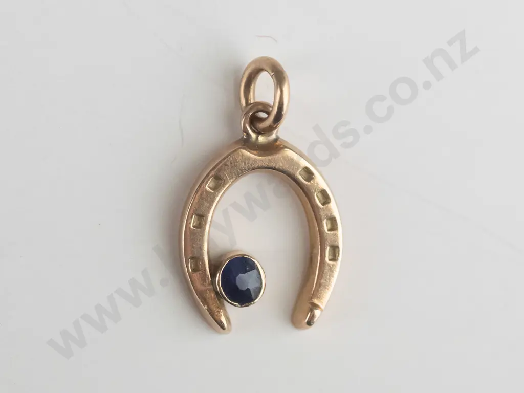 9ct gold horse shoe charm with small oval blue stone in rubover setting Image 1++