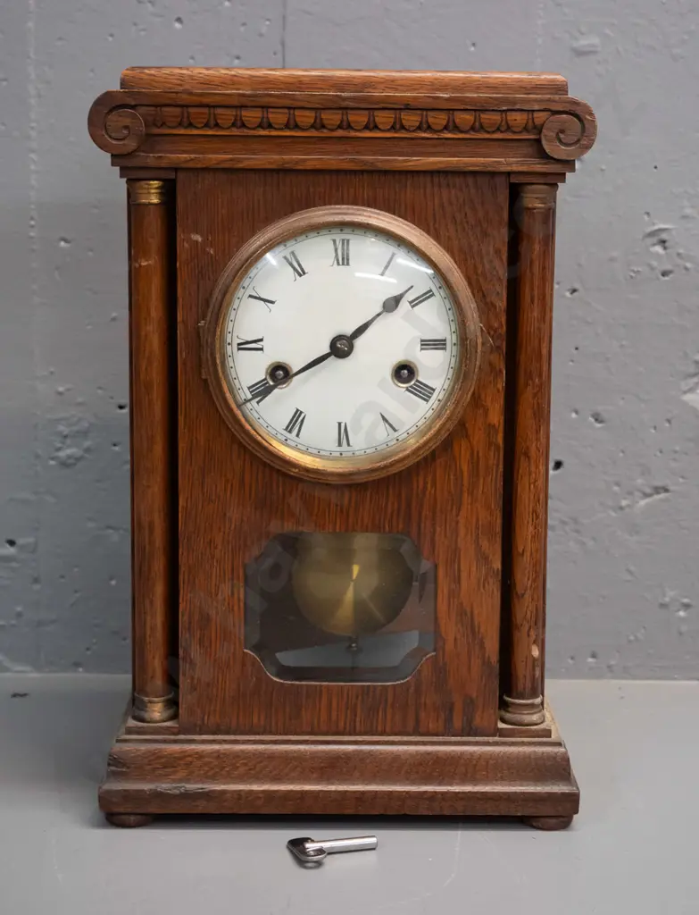 vintage oak cased chiming mantel clock with glazed door, porcelain face, brass bezel and turned columns, missing one Image 1++
