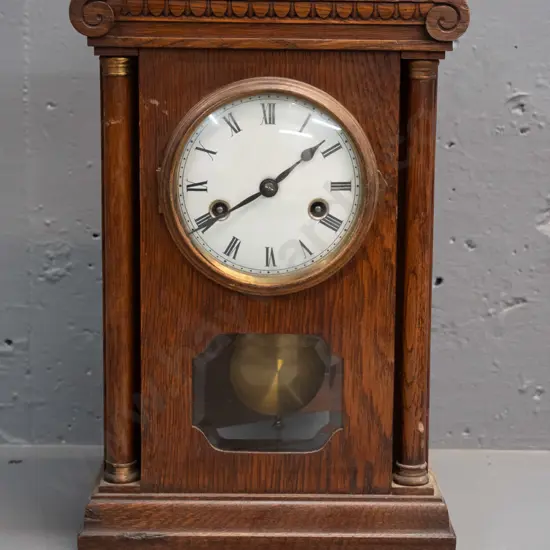 vintage oak cased chiming mantel clock with glazed door, porcelain face, brass bezel and turned columns, missing one