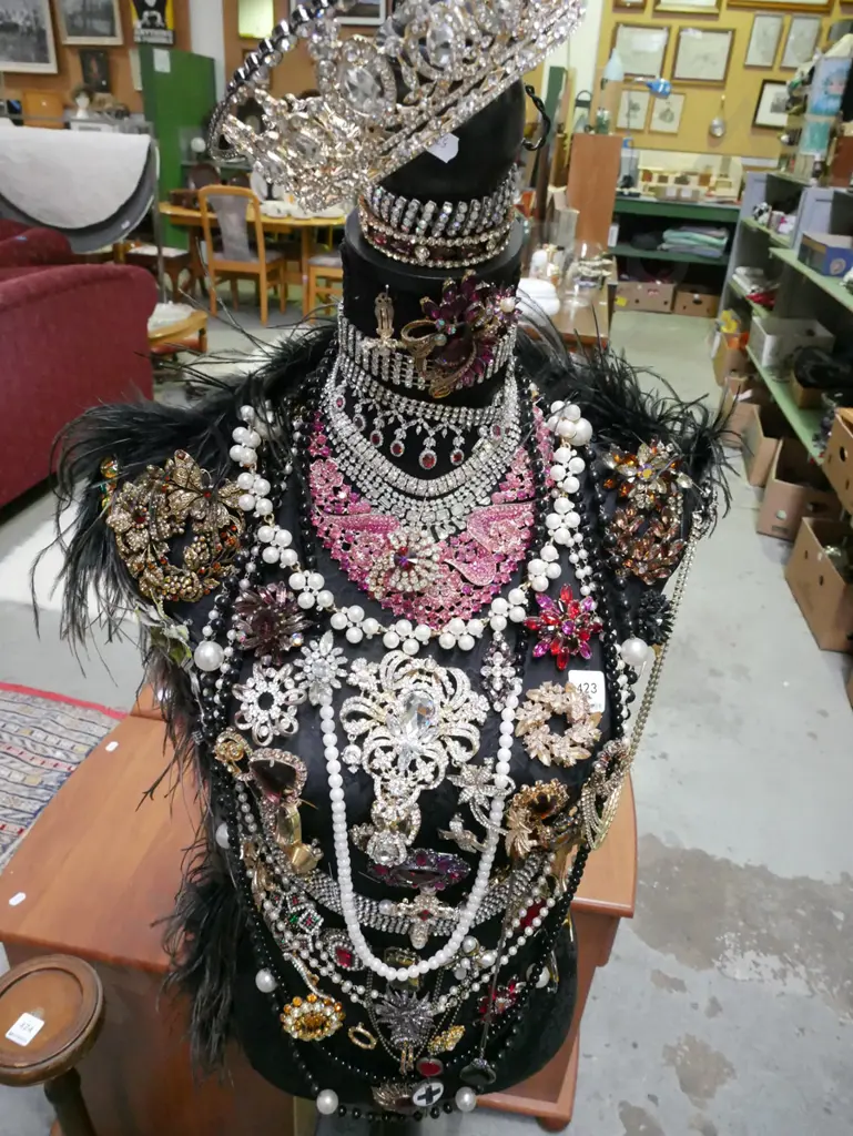 black fabric upholstered torso on stand with numerous pieces of costume jewellery Image 1++