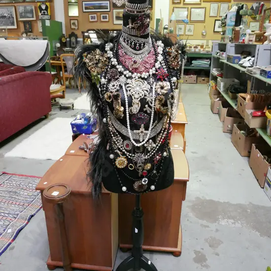 black fabric upholstered torso on stand with numerous pieces of costume jewellery
