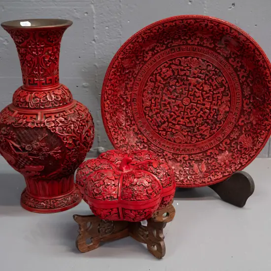 3 cinnabar style composite items - vase, plate with stand, and gourd shaped lidded container on pierced wooden stand.