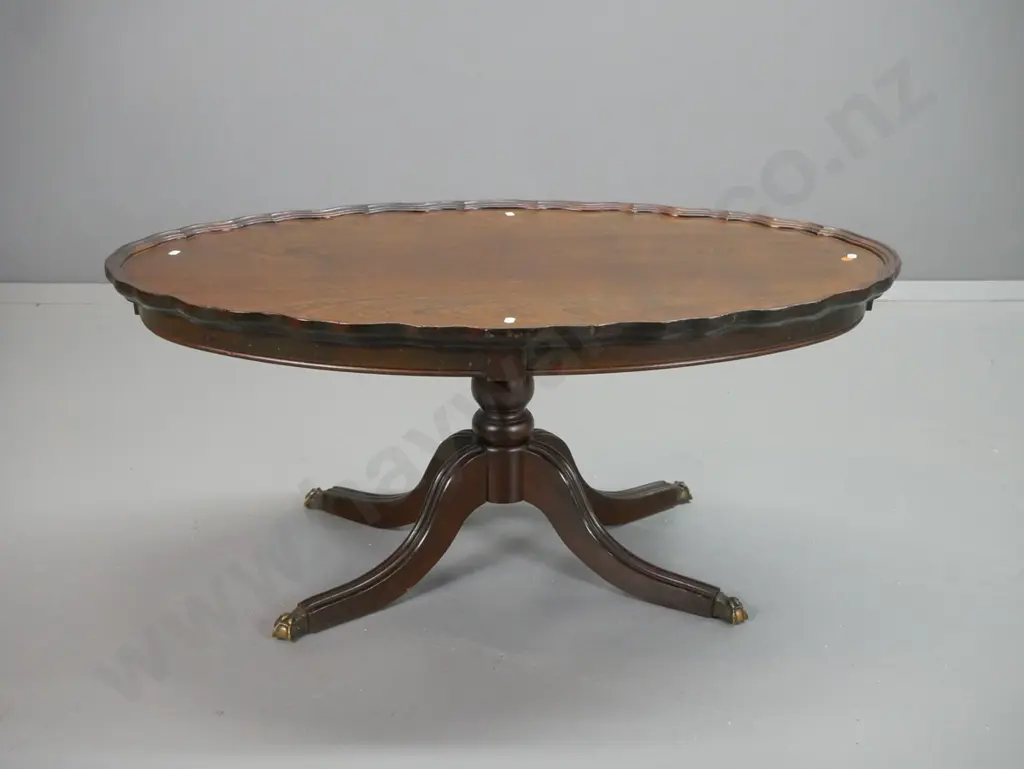 reproduction walnut oval coffee table with raised shaped edge, column base on 4 sweeping legs w/brass paw feet - top and Image 1++