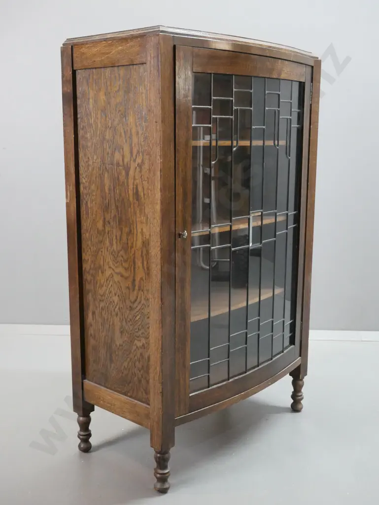oak arts & crafts style display cabinet with panelled sides, one bowed leadlight door, 3 fixed shelves, on short turned Image 1++
