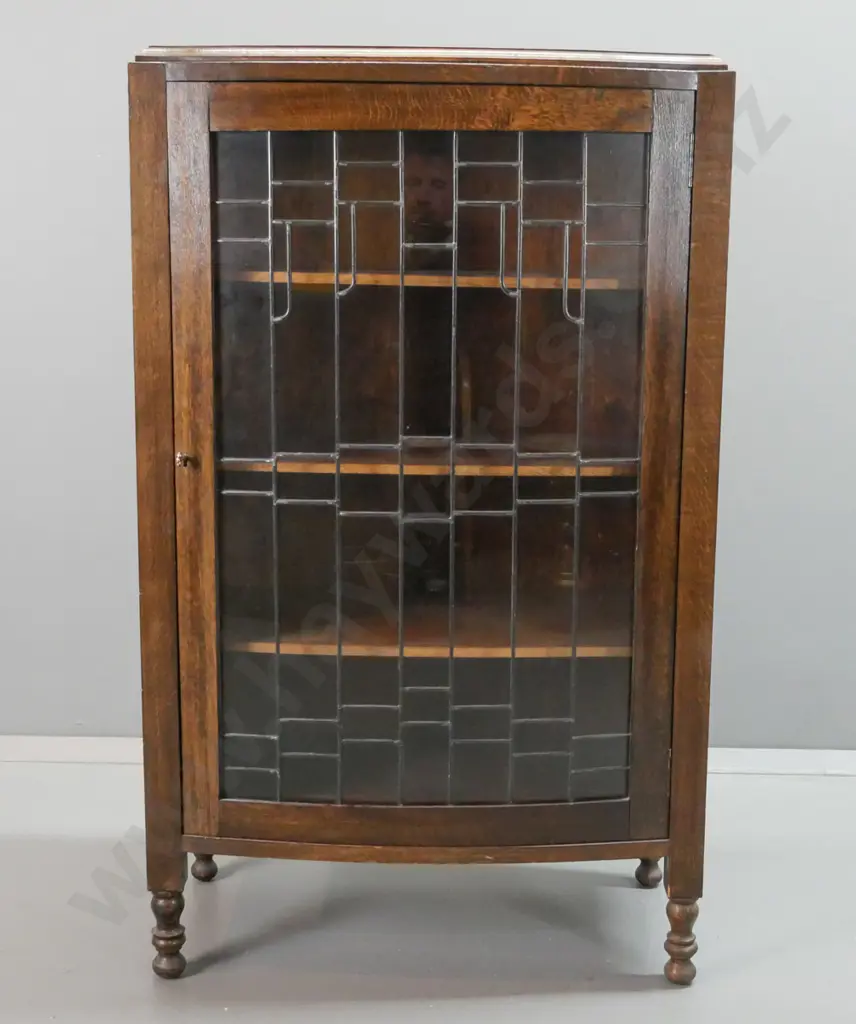 oak arts & crafts style display cabinet with panelled sides, one bowed leadlight door, 3 fixed shelves, on short turned Image 1++