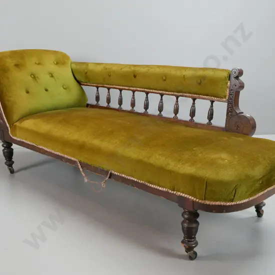Edwardian beech rail-back chaise longue with carved foliate decoration, turned legs on casters, olive green buttoned