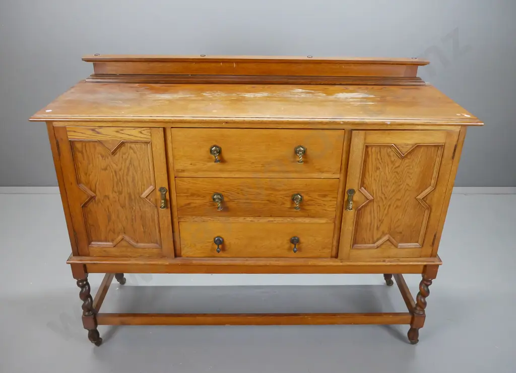 vintage oak Tudor style sideboard with 2 panelled doors, 3 drawers, brass drop handles, stretcher base with twist legs Image 1++