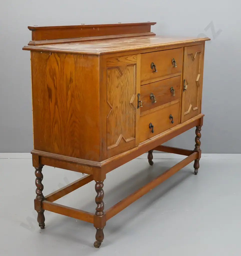 vintage oak Tudor style sideboard with 2 panelled doors, 3 drawers, brass drop handles, stretcher base with twist legs Image 1++